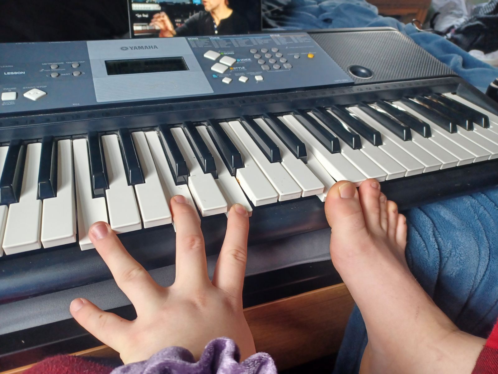 person playing piano with one hand and their toes